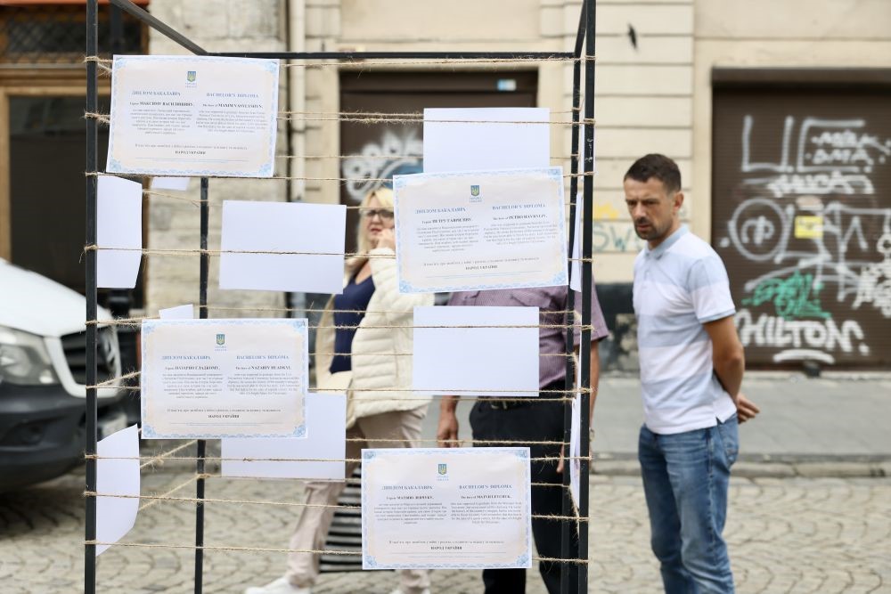Прохожие читают дипломы, выставленные на акци в память погибших на войне студентов во Львове. Фото пресс-служба Львовского горсовета.