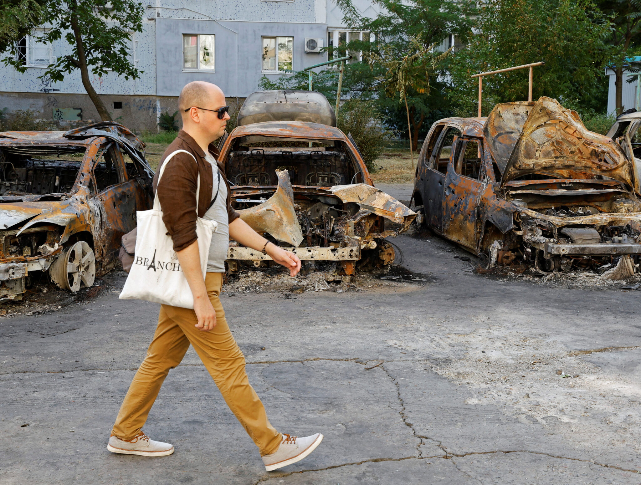 Житель Энергодара на фоне автомобилей, сожженных после обстрела города. Фото REUTERS/Alexander Ermochenko/Scanpix/LETA