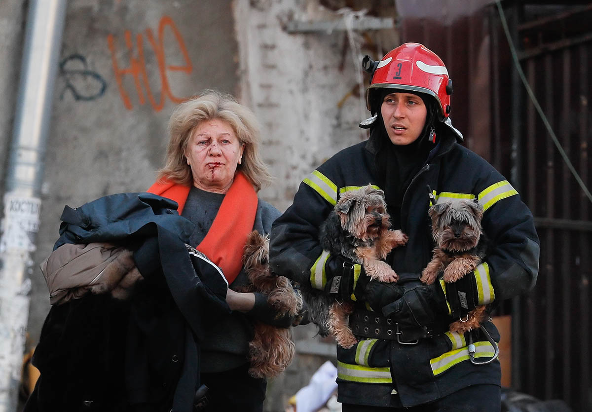 Спасатель помогает раненой женщине и ее собакам после российского обстрела в Киеве. 10 октября 2022 года. Фото SERGEY DOLZHENKO/EPA/Scanpix/LETA