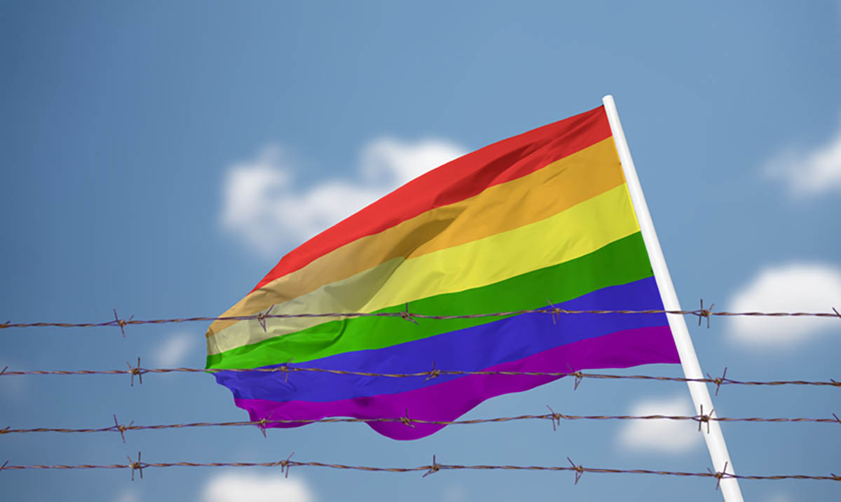 Флаг ЛГБТ за забором из колючей проволоки. Фото Cunaplus_M.Faba по лицензии Istockphoto