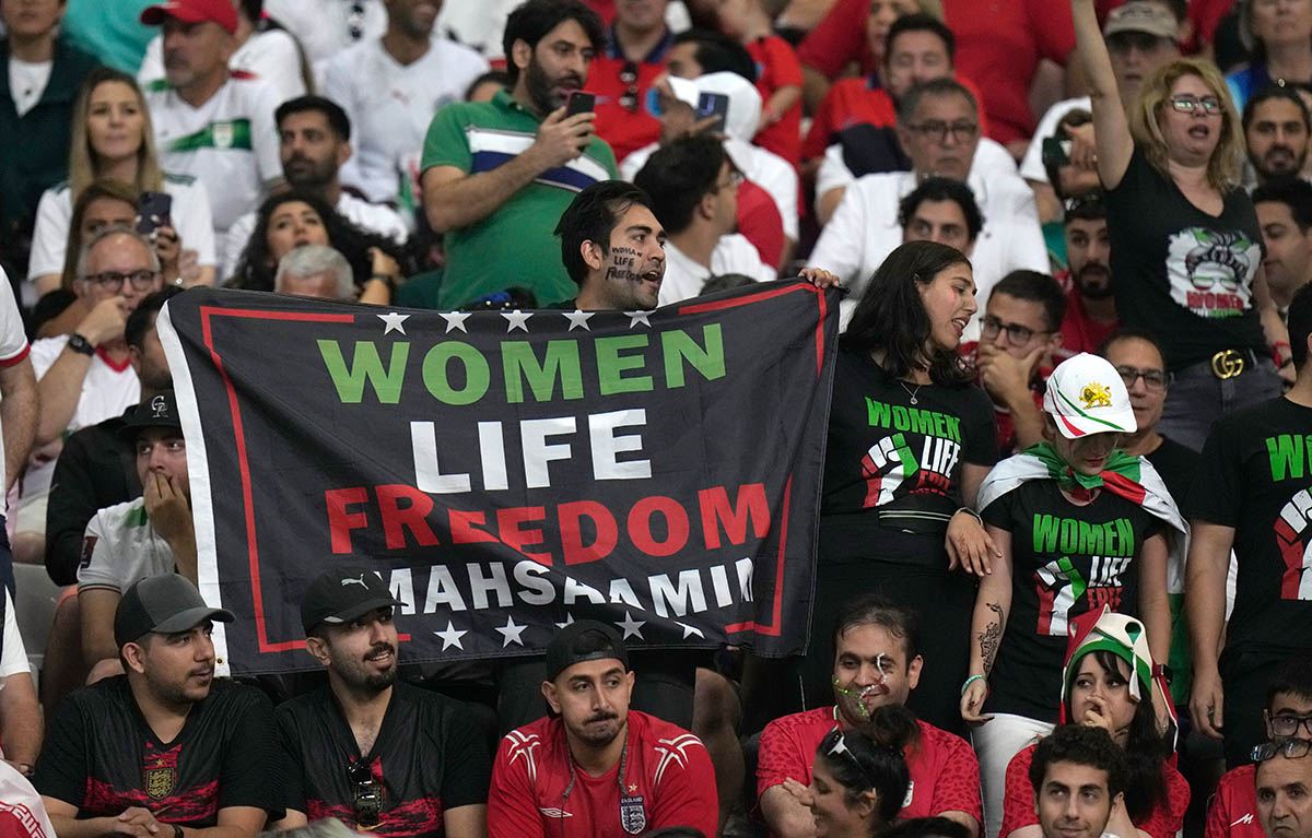Иранский футбольный фанат держит табличку с надписью Life Freedom Masha Amini перед футбольным матчем группы B чемпионата мира между Англией и Ираном на международном стадионе «Халифа» в Дохе, Катар, понедельник, 21 ноября 2022 года. Фото AP/Alessandra Tarantino