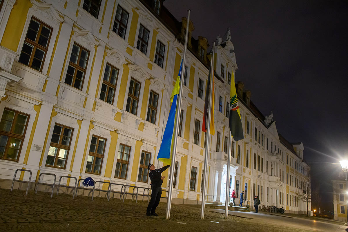 Полицейский поднимает флаг Украины перед зданием парламента земли Саксония-Анхальт, Германия. 24 февраля 2023 года. Фото Klaus-Dietmar Gabbert/dpa/Scanpix/Leta