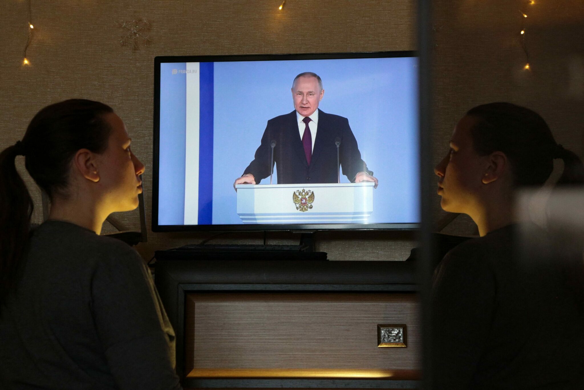 Девушка слушает выступление Владимира Путина по телевизору. Фото AFP/Scanpix/LETA