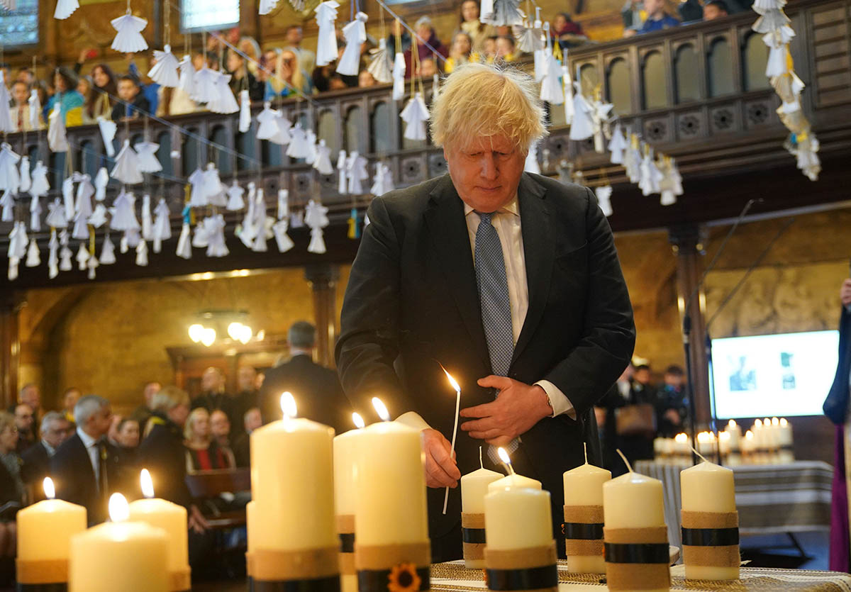 Бывший премьер-министр Борис Джонсон зажигает свечу во время экуменического молебна в Украинском католическом соборе в Лондоне. 24 февраля 2023 года. Фото Yui Mok/AP/Scanpix/Leta