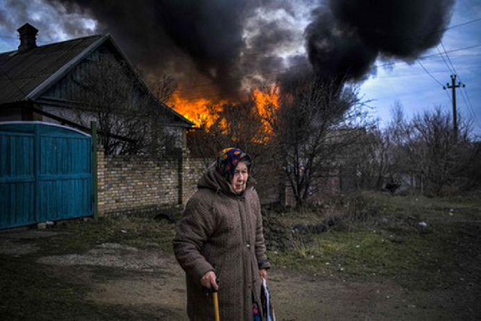 Женщина на фоне горящего дома в селе Константиновка Донецкой области. Фото Sergey Shestak/AFP/Scanpix/LETA