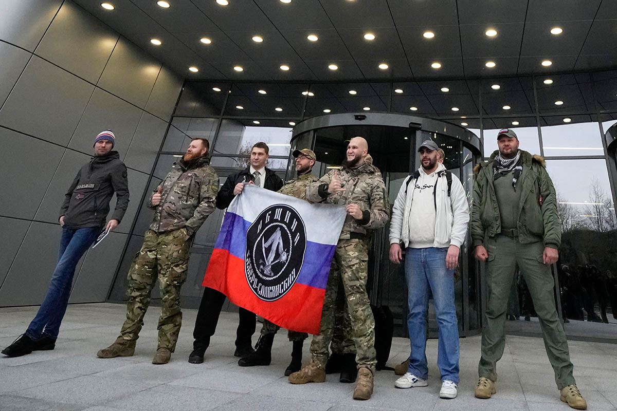 Мужчины в военной камуфляжной форме позируют у входа в ЧВК «Вагнер-Центр». Фото AP Photo/Scanpix/LETA