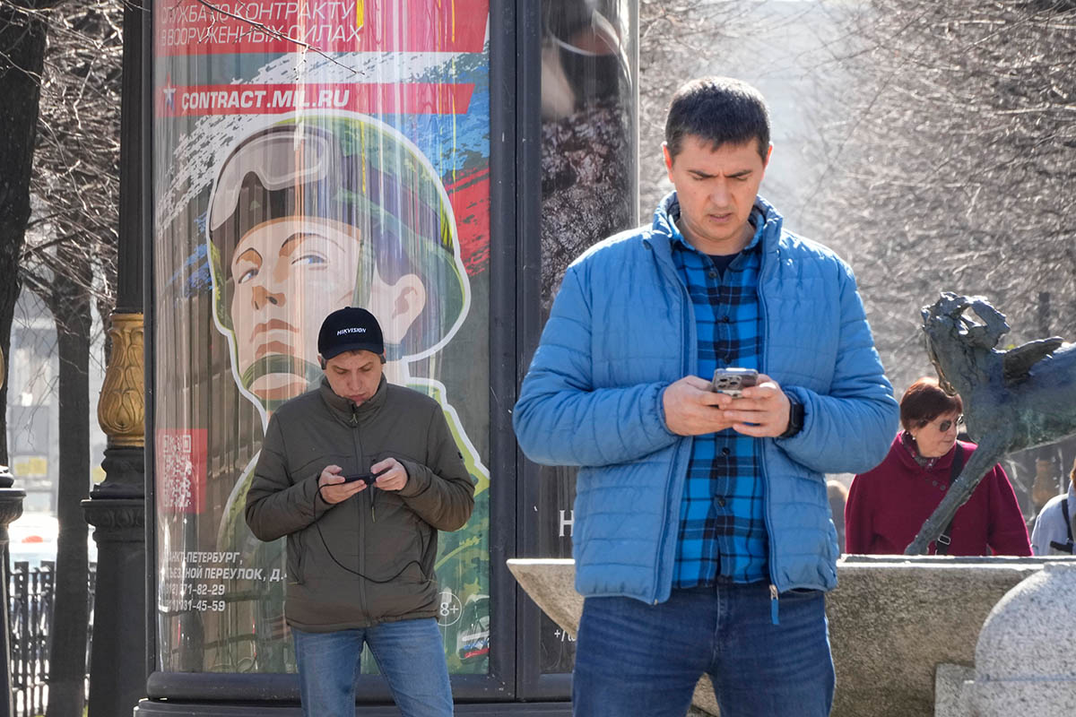 Мужчины у рекламного щита призывающего в армию «Военная служба по контракту в вооруженных силах», Санкт-Петербург. Апрель 2023 года. Фото Dmitri Lovetsky/AP Photo/Scanpix/LETA