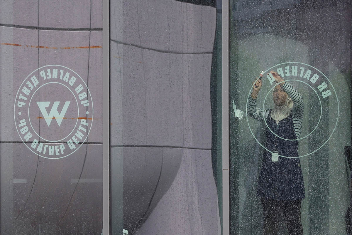 Сотрудница снимает логотип с окна «ЧВК Вагнер Центра» в Санкт-Петербурге. Фото Anton Vaganov/REUTERS/Scanpix/LETA