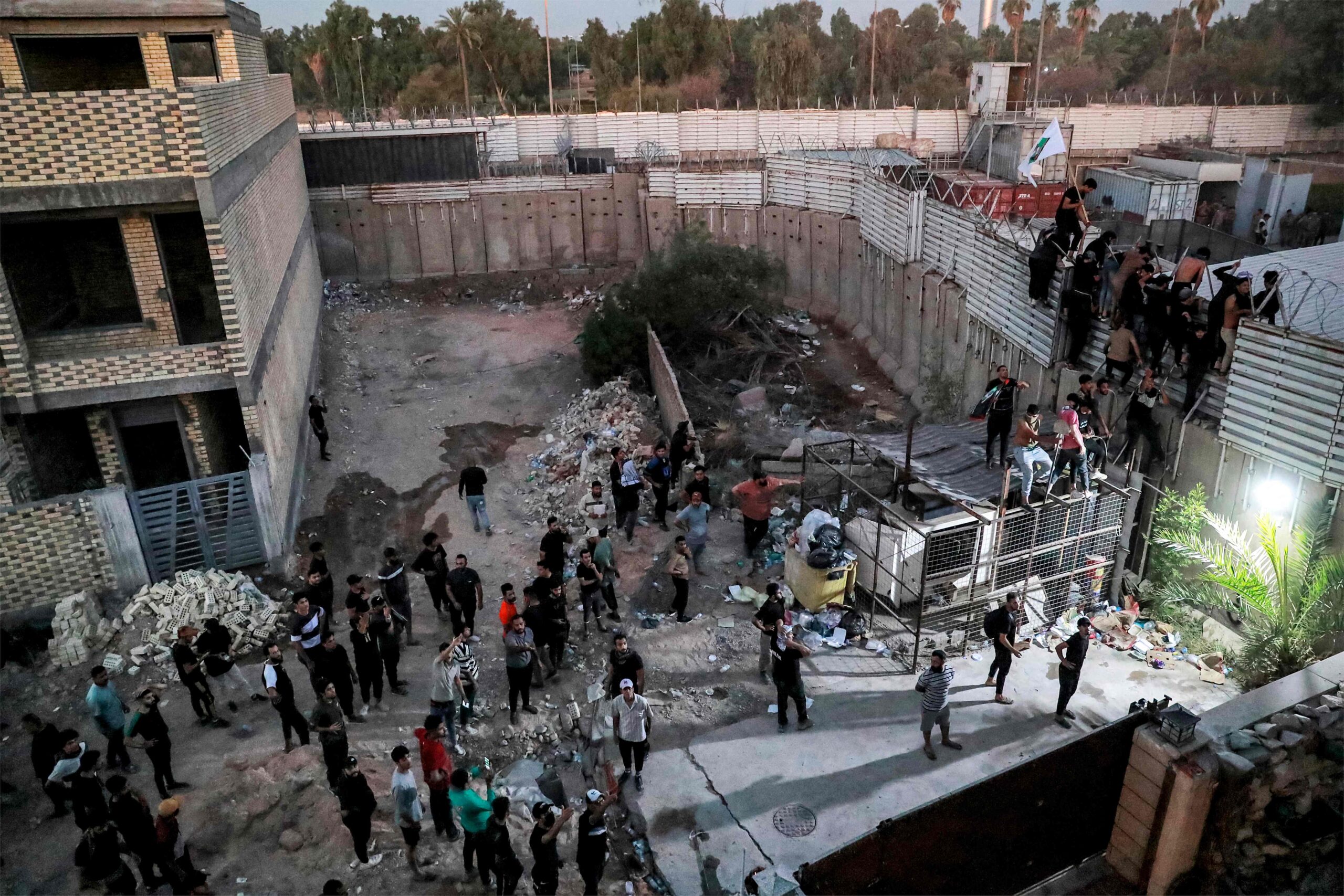 Участники акции протеста в Ираке перелазят через стену посольства Швеции 20 июля 2023 года. Фото AHMAD AL-RUBAYE / AFP / Scanpix / LETA.