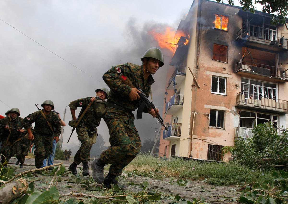 Грузинские солдаты бегут возле горящего здания после российского обстрела в Гори, в 80 км от Тбилиси, 9 августа 2008 года. Фото Gleb Garanich/REUTERS/Scanpix/LETA