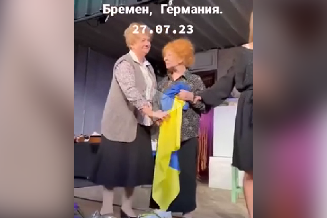 Лия Ахеджакова с украинском флагом на спектакле в Бремене. Скриншот из видео «Газета.Ру».