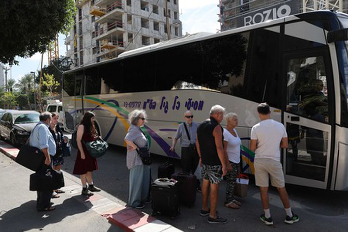 Мирные жители стоят в очереди на посадку в автобус, доставляющий их в гостиницу в Тель-Авиве, 7 октября 2023 года после ракетной атаки из сектора Газа и проникновения палестинских формирований на территорию Израиля. Фото Jack Guez/AFP/Scanpix/LETA