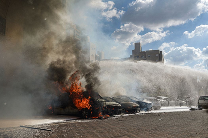 Сотрудники пожарной бригады пытаются потушить горящие автомобили после ракетного обстрела из сектора Газа. Фото Ilia Yefimovich/dpa/Scanpix/LETA