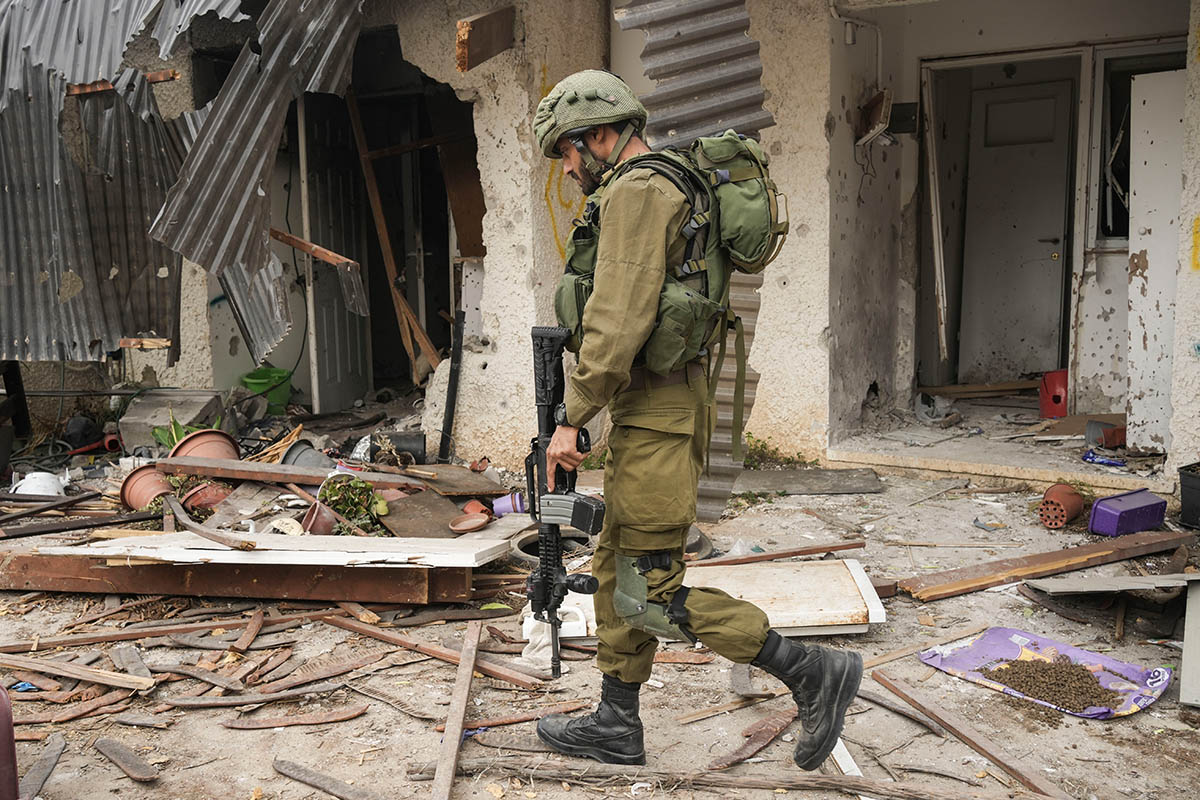 Израильский солдат проходит в кибуце Кфар-Азза мимо дома, повреждённого во время нападения ХАМАС. Фото Maya Alleruzzo/AP Photo/Scanpix/LETA