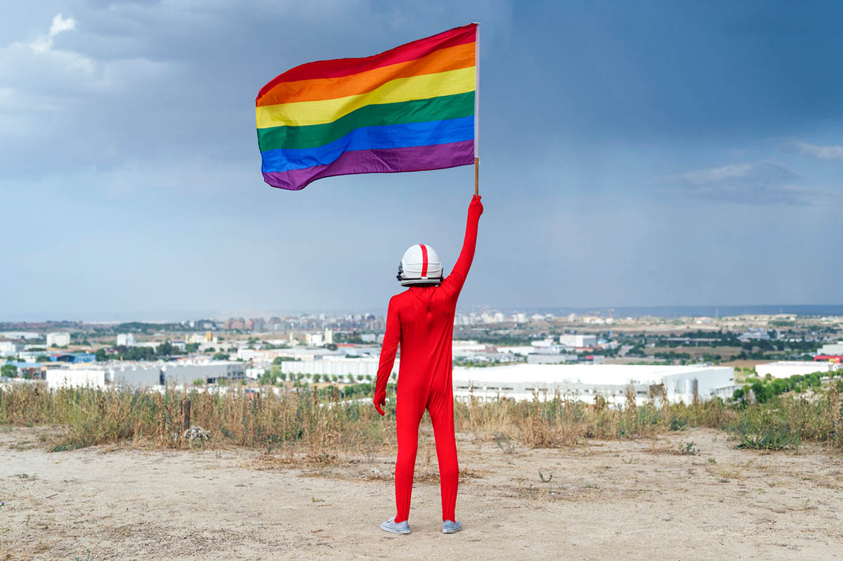 Человек в красном костюме с флагом ЛГБТ. Фото MIGUEL ANGEL PARTIDO GARCIA/istockphoto