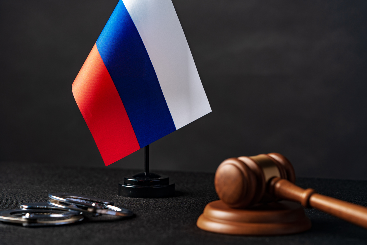 Флаг России с судейским молотком и наручниками. Фото FabrikaCr/Istockphoto