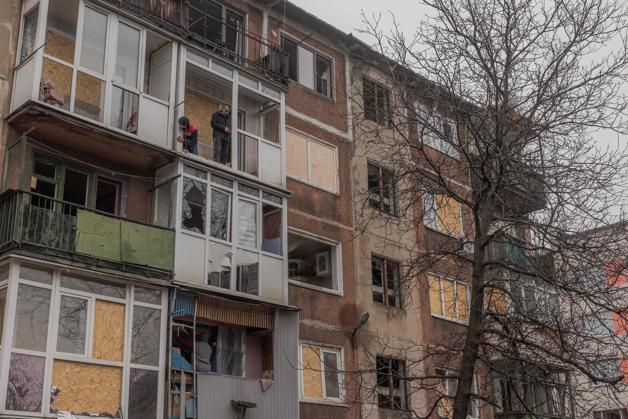 Местные жители ремонтируют балкон в поврежденном жилом доме после ночного обстрела в Мирнограде Донецкой области 26 января 2024 года