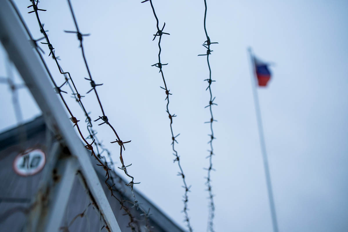Забор с колючей проволокой и флаг РФ. Фото Semen Salivanchuk/istockphoto