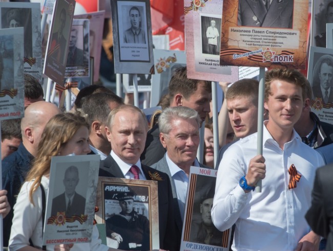 2842509 05/09/2016 May 9, 2016. Russian President Vladimir Putin, center, carries a portrait of his father war veteran Vladimir as he takes part in the Immortal Regiment march on Red Square, Moscow. Sergey Guneev/Sputnik
