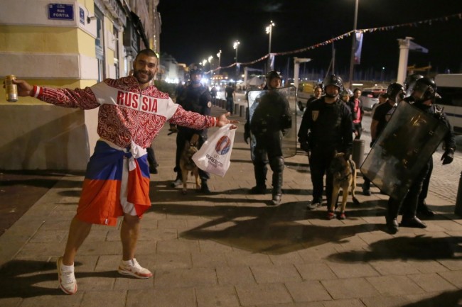 2869839 06/12/2016 A Russian football fan stands by police officers on a street in Marseilles during an unrest after the UEFA Euro 2016 group stage match between the English and Russian national teams. Vitaliy Belousov/Sputnik