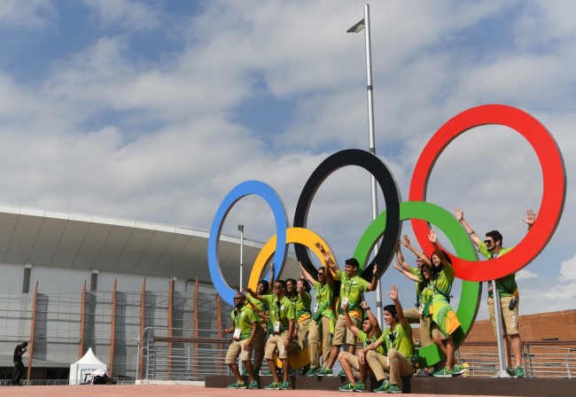 Волонтеры рядом с олимпийскими кольцами. Фото: Sputnik / Scanpix