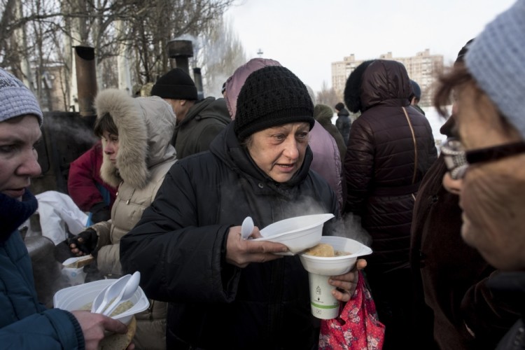Local residents get free food in Avdiivka, eastern Ukraine, Wednesday, Feb. 1, 2017. Freezing residents of an eastern Ukraine town battered by an upsurge in fighting between government troops and Russia-backed rebels flocked to a humanitarian aid center Wednesday to receive food and warm up. (AP Photo/Evgeniy Maloletka)
