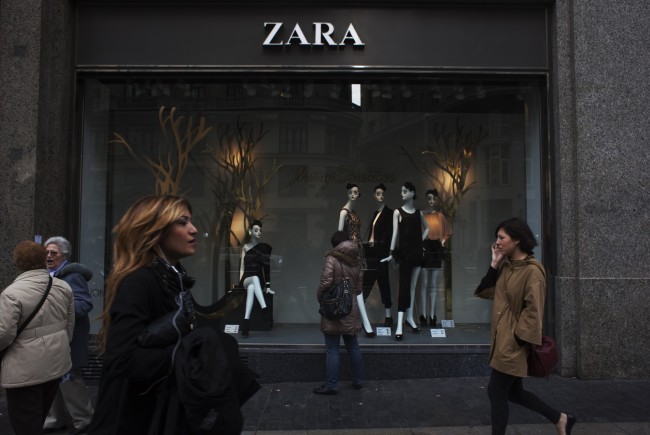 People walk by one of Zara's stores in central Madrid December 14, 2011. Sales growth at Spain's Inditex, the world's largest clothing retailer and owner of the popular Zara label, eased in the third quarter as the euro zone debt crisis rattled shoppers and unseasonably good autumn weather altered spending patterns. But the company, founded by Spain's richest man Amancio Ortega, still cheered the market with evidence it remains capable of outperforming rivals. The group reported a surprise 100 basis point increase in its profit margin and said sales growth in the fourth quarter had recovered. REUTERS/Susana Vera (SPAIN - Tags: BUSINESS SOCIETY)