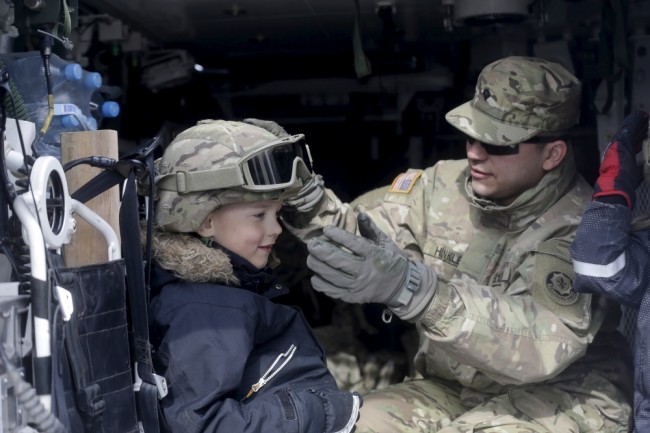 Американский военнослужащий примеряет шлем  эстонскому  мальчику. Фото Reuters/Scanpix