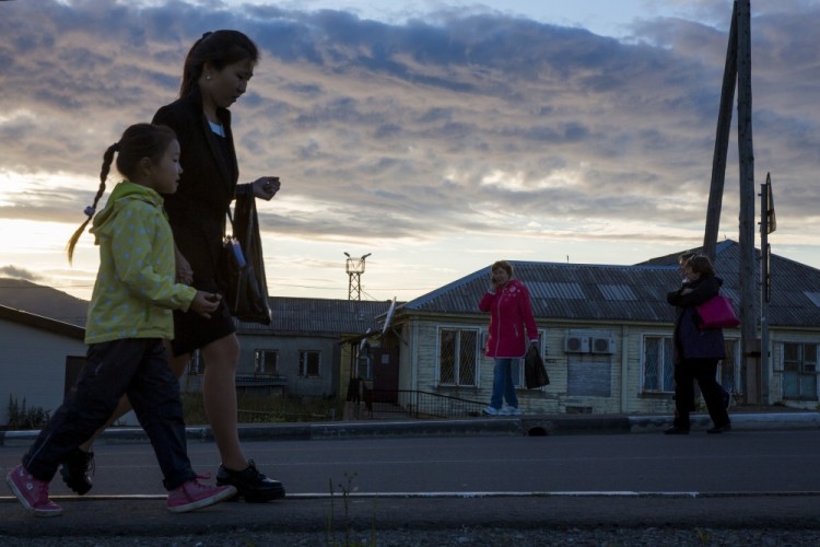 People walk at sunset in the centre of Yuzhno-Kurilsk, the main settlement on the Southern Kurile Island of Kunashir September 15, 2015. Russian residents of the island chain at the centre of a dispute between Japan and Russia that has held up a treaty to formally end World War Two hope a diplomatic solution will lure tourists and investment to help refurbish rickety infrastructure. The Southern Kuriles are referred to in Japan as the Northern Territories. Picture taken September 15, 2015. REUTERS/Thomas Peter