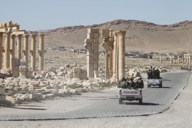 FILE PHOTO: Syrian army soldiers drive past the Arch of Triumph in the historic city of Palmyra, in Homs Governorate, Syria April 1, 2016. REUTERS/Omar Sanadiki/File Photo