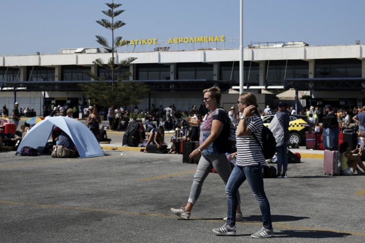 Tourists are gathered outside the passenger terminal of the Kos International Airport 