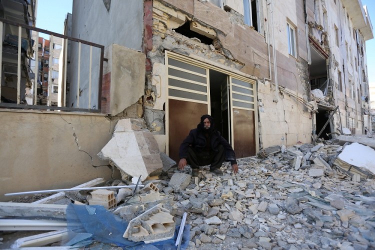 A man sits outside a damaged belonging following an earthquake in Sarpol-e Zahab county in Kermanshah, Iran November 13, 2017. REUTERS/Tasnim News Agency  ATTENTION EDITORS - THIS PICTURE WAS PROVIDED BY A THIRD PARTY.