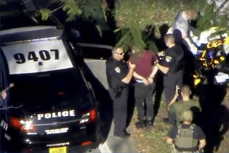 A man placed in handcuffs is led by police near Marjory Stoneman Douglas High School following a shooting incident in Parkland, Florida, U.S. February 14, 2018 in a still image from video.  WSVN.com via REUTERS. ATTENTION EDITORS - THIS IMAGES HAS BEEN PROVIDED BY A THIRD PARTY. NO RESALES, NO ARCHIVES. MANDATORY CREDIT. NO ACCESS SOUTHEAST FLORIDA MEDIA.