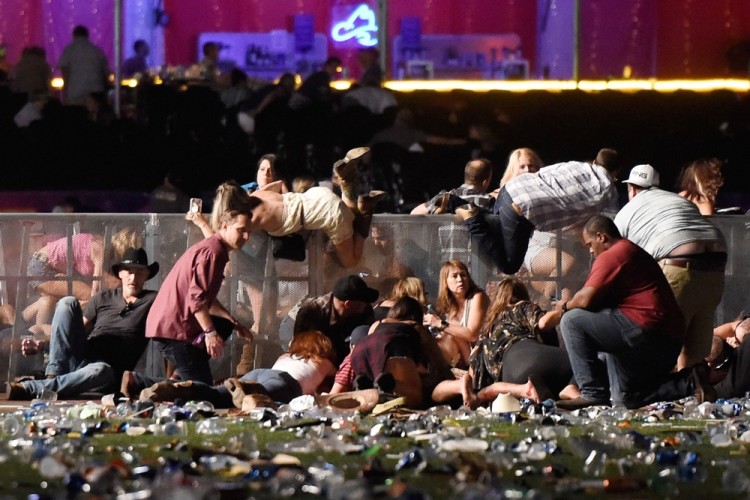 TOPSHOT - LAS VEGAS, NV - OCTOBER 01: People scramble for shelter at the Route 91 Harvest country music festival after apparent gun fire was heard on October 1, 2017 in Las Vegas, Nevada. A gunman has opened fire on a music festival in Las Vegas, leaving at least 20 people dead and more than 100 injured. Police have confirmed that one suspect has been shot. The investigation is ongoing.   David Becker/Getty Images/AFP / AFP PHOTO / GETTY IMAGES NORTH AMERICA / David Becker