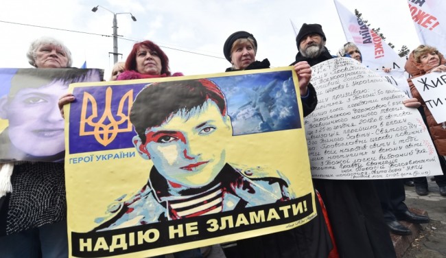 Protesters hold portraits of jailed female Ukrainian pilot Nadiya Savchenko during a rally in front of Russian embassy in Kiev on March 9, 2016. The placard reads : 
