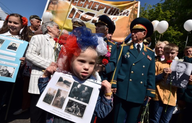 A girl wearing a bow in the colors of the Russian flag attends the Immortal Regiment march in the Ukrainian capital of Kiev on May 9, 2016, during Victory Day celebrations to commemorate the former Soviet Union's victory over Nazi Germany in World War II. / AFP PHOTO / GENYA SAVILOV