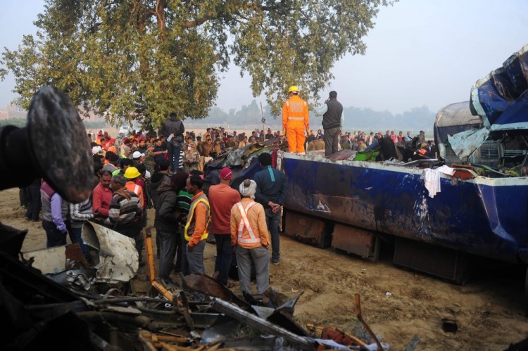 Rescue worker and onlookers stand near the wreckage of the train on the damaged tracks where a train derailed near Pukhrayan in India's Kanpur district on November 21, 2016. Emergency workers raced to find any more survivors in the mangled wreckage of an Indian train that derailed on November 20, killing at least 120 people, in the worst disaster to hit the country's ageing rail network in recent years. / AFP PHOTO / SANJAY KANOJIA