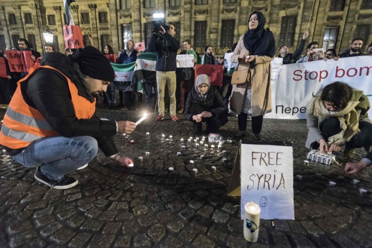 На амстердамской площади в память о жертвах сирийского конфликта зажигали свечи — под флагами оппозиции. Фото: AFP / Scanpix
