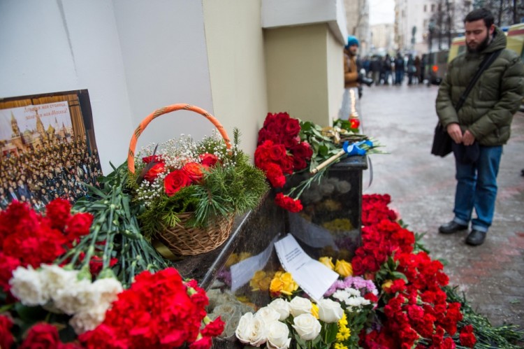 A man lays flowers at the home stage building of the Alexandrov Ensemble (The Red Army Choir), in Moscow on December 25, 2016. The Russian military plane crashed on its way to Syria on December 25, with no sign of survivors among the 92 onboard, who included dozens of Red Army Choir members heading to celebrate the New Year with troops. Russia's defence ministry said a body had been recovered from the Black Sea. / AFP PHOTO / Alexander UTKIN