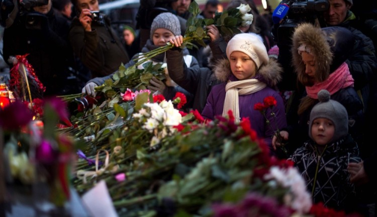 Children lay flowers at the home stage building of the Alexandrov Ensemble (The Red Army Choir), in Moscow, on December 25, 2016, after a Russian military plane which included dozens of Red Army Choir members crashed.  The Russian military plane crashed on its way to Syria on December 25, with no sign of survivors among the 92 onboard, who included dozens of Red Army Choir members heading to celebrate the New Year with troops. Russia's defence ministry said a body had been recovered from the Black Sea. / AFP PHOTO / Alexander UTKIN
