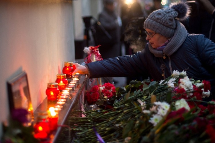 A woman lays flowers at the home stage building of the Alexandrov Ensemble (The Red Army Choir), in Moscow, on December 25, 2016, after a Russian military plane which included dozens of Red Army Choir members crashed.  The Russian military plane crashed on its way to Syria on December 25, with no sign of survivors among the 92 onboard, who included dozens of Red Army Choir members heading to celebrate the New Year with troops. Russia's defence ministry said a body had been recovered from the Black Sea. / AFP PHOTO / Alexander UTKIN