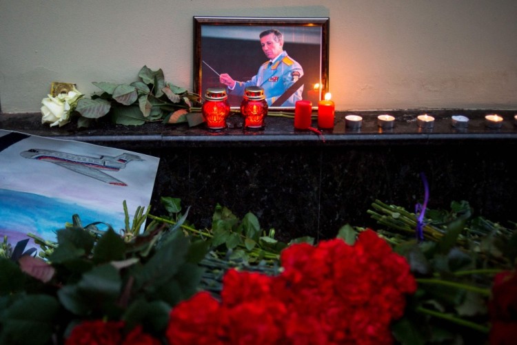 A picture shows a portrait of Valery Khalilov, Chief conductor and artistic director of Alexandrov song and dance ensemble placed next to candles, flowers and a drawing of a plane at the home stage building of the Alexandrov Ensemble (The Red Army Choir), in Moscow, on December 25, 2016, after a Russian military plane which included dozens of Red Army Choir members crashed.  The Russian military plane crashed on its way to Syria on December 25, with no sign of survivors among the 92 onboard, who included dozens of Red Army Choir members heading to celebrate the New Year with troops. Russia's defence ministry said a body had been recovered from the Black Sea. / AFP PHOTO / ALEXANDER UTKIN