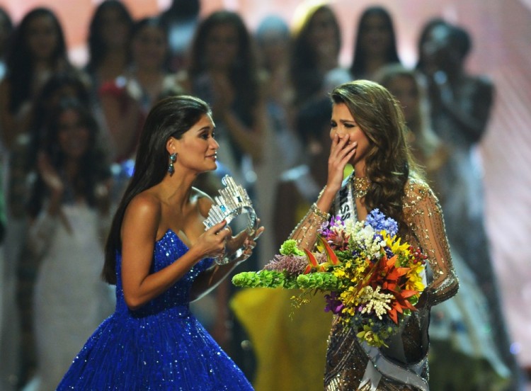 Miss Universe candidate Iris Mittenaere (R) of France reacts after winning the title while former Miss Universe Pia Wurzbach of the Pilippines prepares to crown her during the finals of the Miss Universe pageant at the Mall of Asia Arena in Manila on January 30, 2017. Miss France was crowned Miss Universe on January 30 in a glitzy spectacle free of last year's dramatic mix-up but with a dash of political controversy as finalists touched on migration and other hot-button global issues. / AFP PHOTO / TED ALJIBE