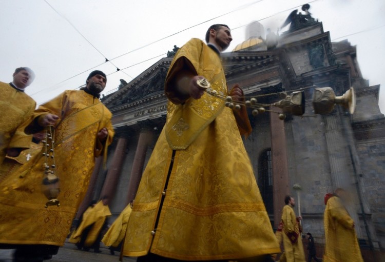 Russian Orthodox priests take part in a procession in front of the Saint Isaac's Cathedral in Saint Petersburg, on February 19, 2017. Believers take part in the rallye to support the city authorities' decision to hand control of the country's largest cathedral to the powerful Russian Orthodox Church. / AFP PHOTO / OLGA MALTSEVA