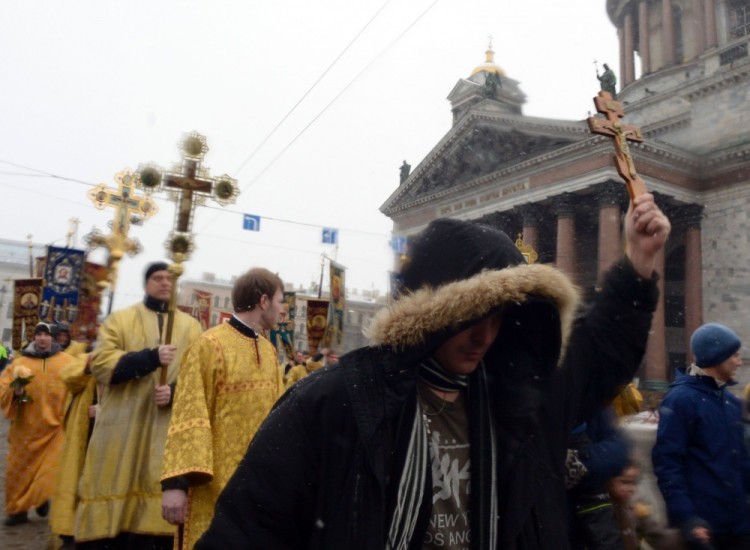 Russian Orthodox believers carry church banners and crosses during the cross walk in front of the Saint Isaac's Cathedral in Saint Petersburg, on February 19, 2017. Believers take part in the rallye to support the city authorities' decision to hand control of the country's largest cathedral to the powerful Russian Orthodox Church. / AFP PHOTO / OLGA MALTSEVA