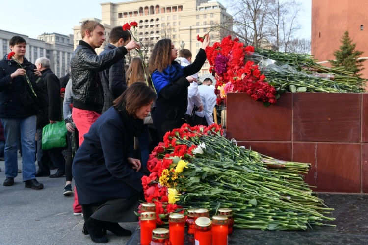 People place flowers in honour of the victims of April 3 blast in the Saint Petersburg metro at a memorial stone reading Leningrad by the Kremlin wall in central Moscow on April 6, 2017. / AFP PHOTO / Natalia KOLESNIKOVA