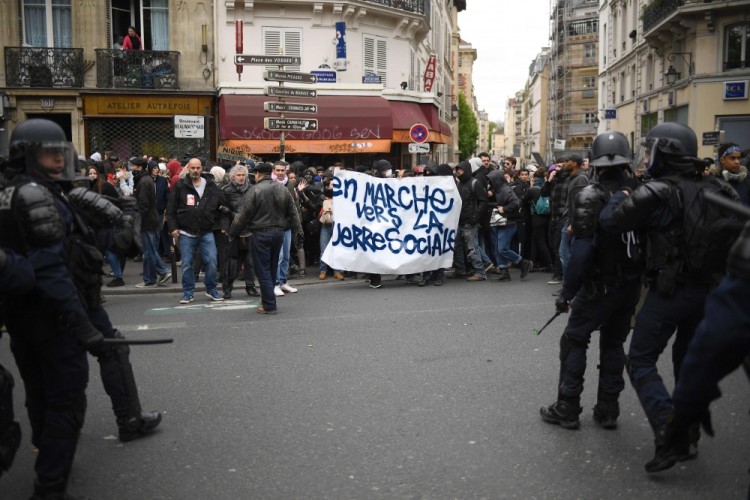 Riot police officers stand in front of people taking part in a demonstration called by the collectif 