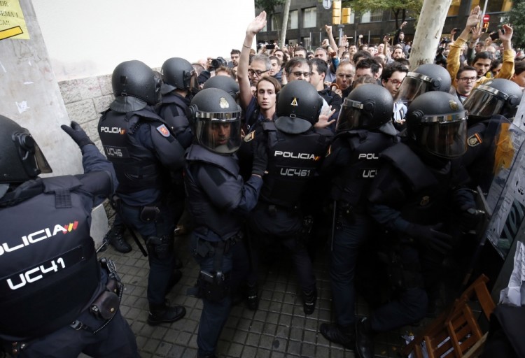 Spanish police officers push people outside a polling station in Barcelona, on October 1, 2017, on the day of a referendum on independence for Catalonia banned by Madrid. More than 5.3 million Catalans are called today to vote in a referendum on independence, surrounded by uncertainty over the intention of Spanish institutions to prevent this plebiscite banned by justice.  / AFP PHOTO / PAU BARRENA
