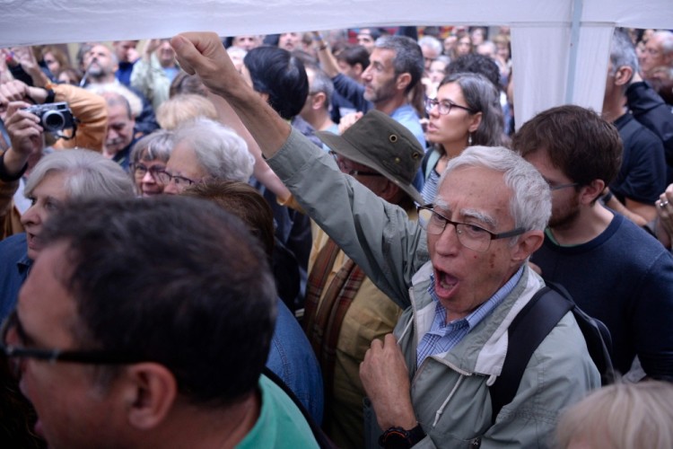 People raise their fists outside a polling station in Barcelona, on October 1, 2017, as they wait to vote on the day of a referendum on independence for Catalonia banned by Madrid. More than 5.3 million Catalans are called today to vote in a referendum on independence, surrounded by uncertainty over the intention of Spanish institutions to prevent this plebiscite banned by justice.  / AFP PHOTO / Josep LAGO