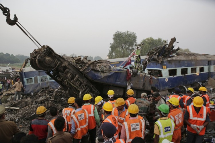 Rescuers search among the debris after 14 coaches of an overnight passenger train rolled off the track near Pukhrayan village Kanpur Dehat district, Uttar Pradesh state, India, Sunday, Nov. 20, 2016. Dozens were killed and dozens more were injured in the accident. (AP Photo/Rajesh Kumar Singh)